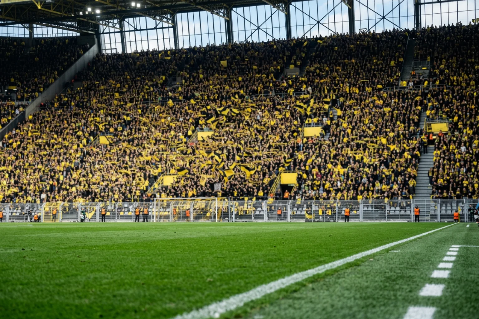 Gele tribune van het stadion in Dortmund vol met fans in geel-zwart shirt boven een groen voetbalveld
